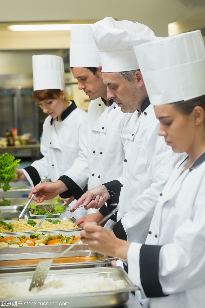 四個廚師在忙碌的廚房里服務托盤